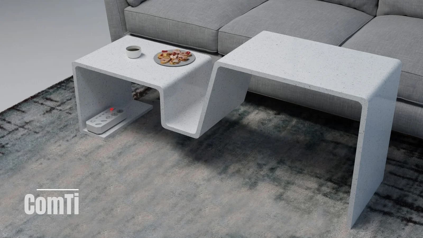White sculptural coffee table with two surfaces at different heights, a central recess and space beneath, placed beside a grey sofa.