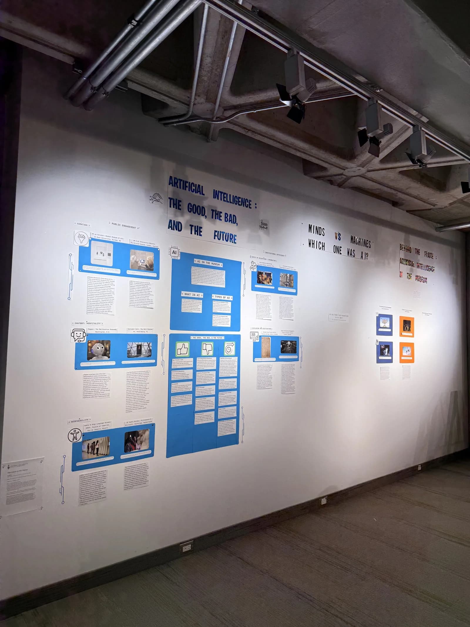 Side view of the exhibition wall with blue interpretation panels and a visitor response table.