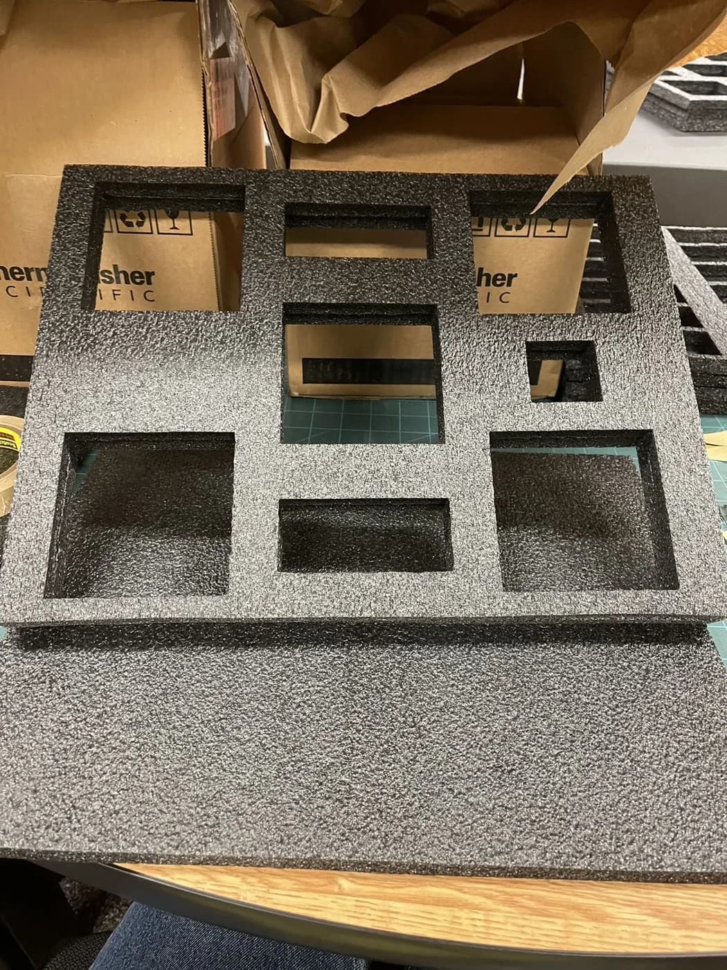 Grey foam inserts with multiple rectangular cutouts are laid on a workbench.