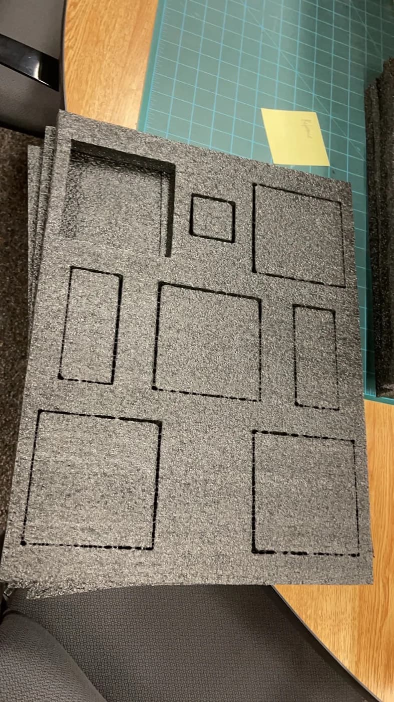 A grey foam sheet has rectangular outlines marked for differently sized object compartments.