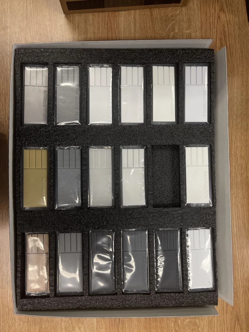 Rows of individually wrapped rectangular specimens are held in foam slots inside an open box.
