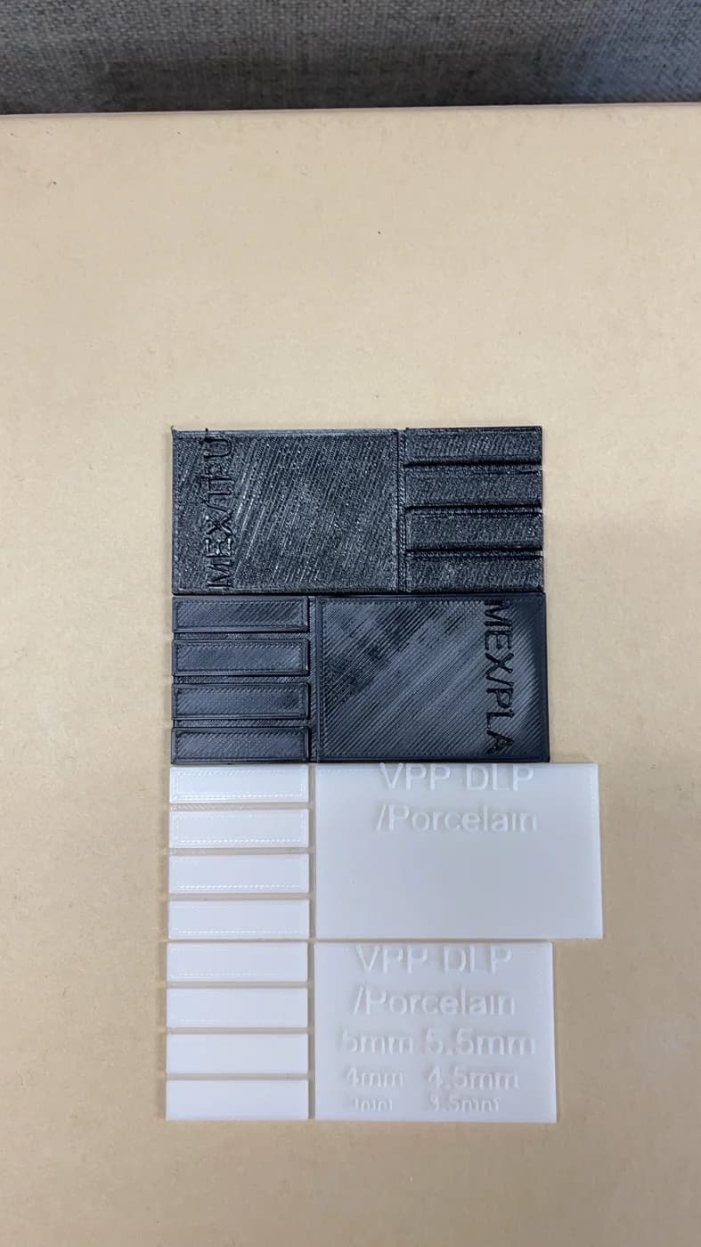 Dark and white rectangular pieces are arranged in overlapping rows on a tabletop, with visible surface lines and relief.